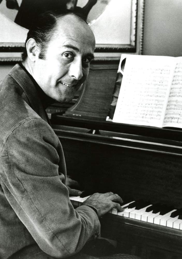 Black and White images of Henry Mancini sitting at a piano looking back over this shoulder and smiling