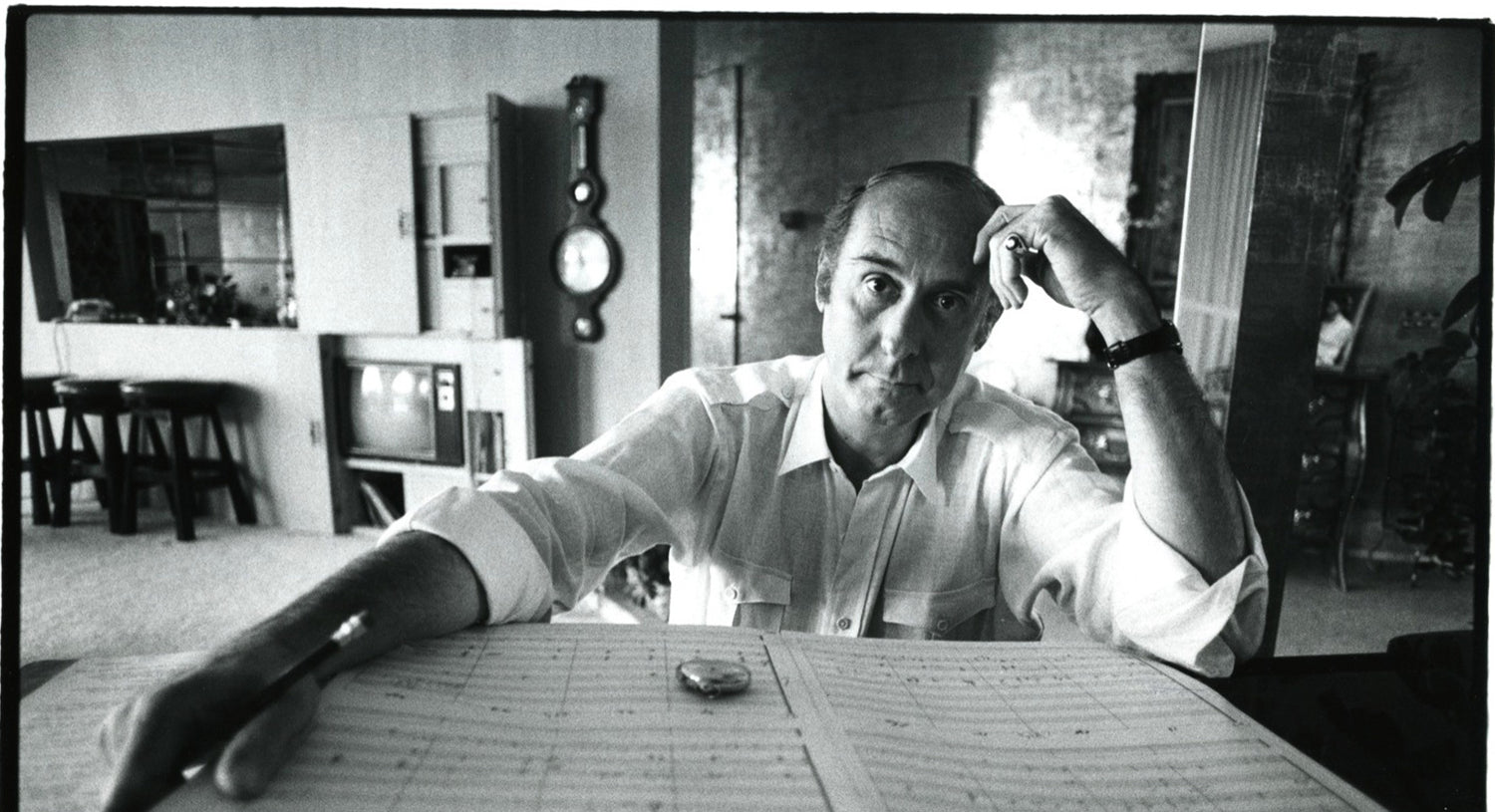 Black and White image of Henry Mancini looking forward with hand on forehead reading a music song sheet